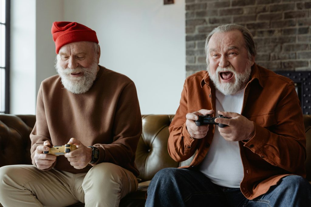Twee mannen spelen ontspannen videogames samen en genieten van hun pensioen dankzij slimme pensioenopbouw via beleggen